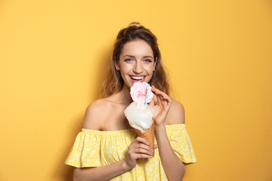 Portrait of young woman holding cotton candy dessert on yellow background