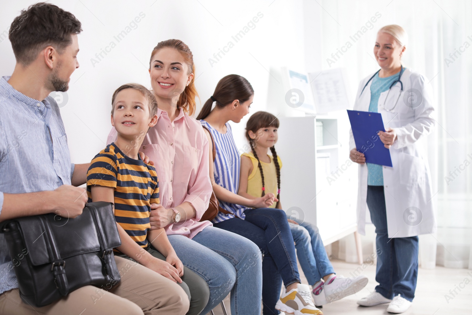 Photo of Parents with children waiting their turn in hospital. Visiting doctor