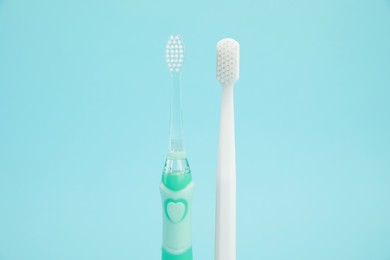 Photo of Electric and plastic toothbrushes on light blue background. Dental care