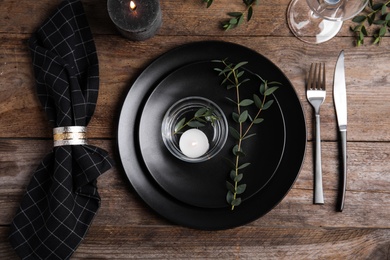 Elegant festive table setting with candle on wooden background, flat lay