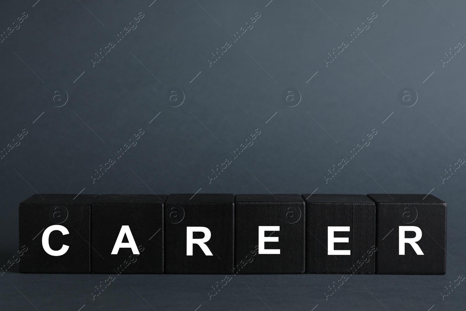 Photo of Black cubes with word CAREER on dark background. Space for text