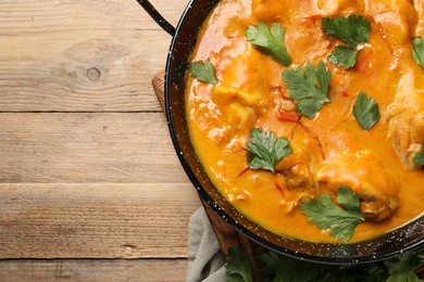 Photo of Tasty chicken curry with parsley on wooden table, top view. Space for text