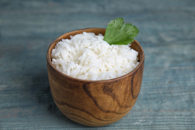 Photo of Bowl with tasty cooked rice on light blue wooden table, closeup