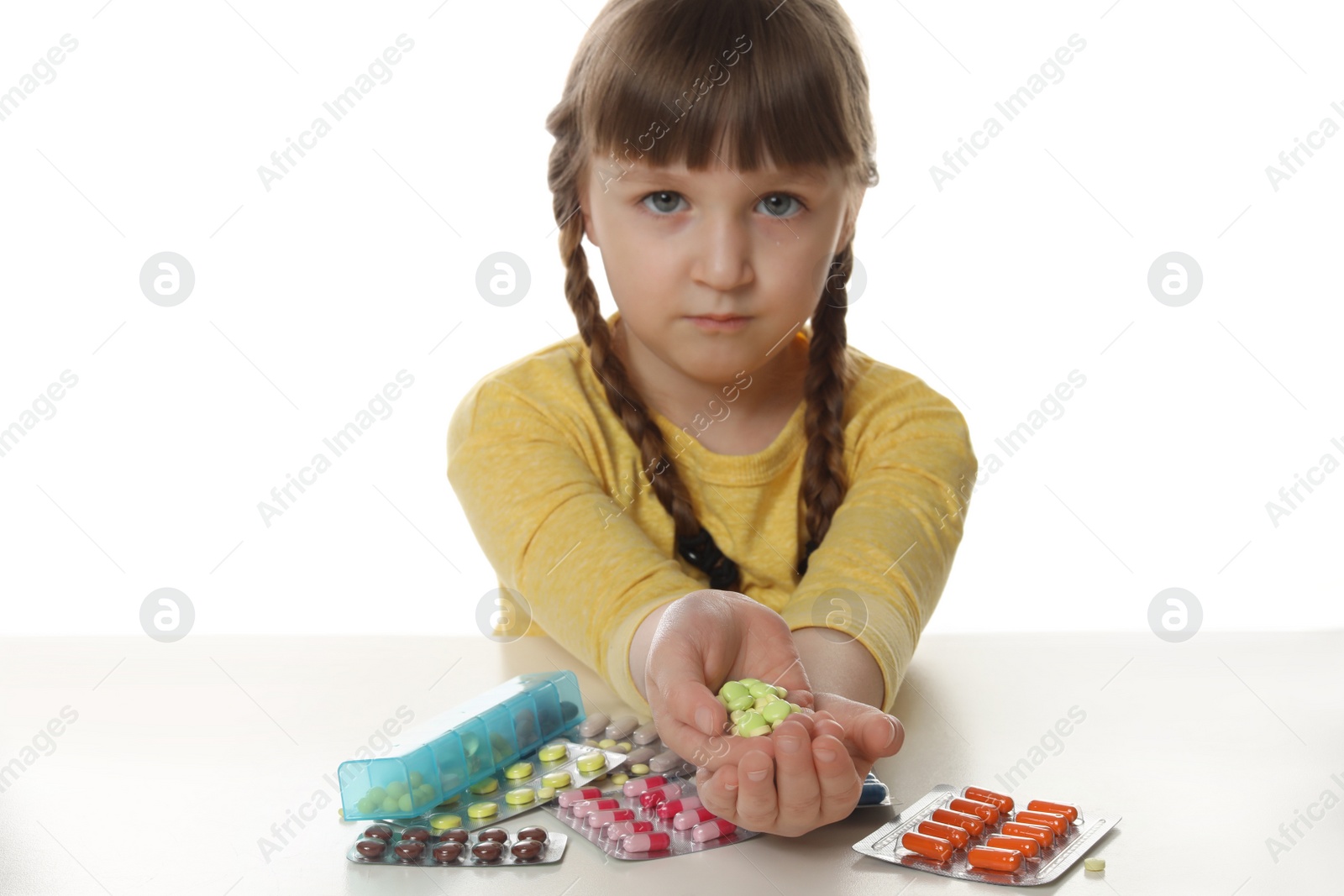 Photo of Little child with many different pills on white background. Danger of medicament intoxication