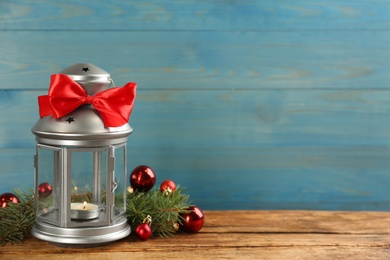 Photo of Lantern with burning candle and Christmas decorations on wooden table. Space for text