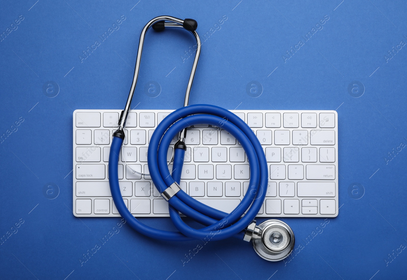 Photo of Computer keyboard with stethoscope on blue background, top view