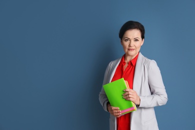 Photo of Portrait of female teacher with notebooks on color background