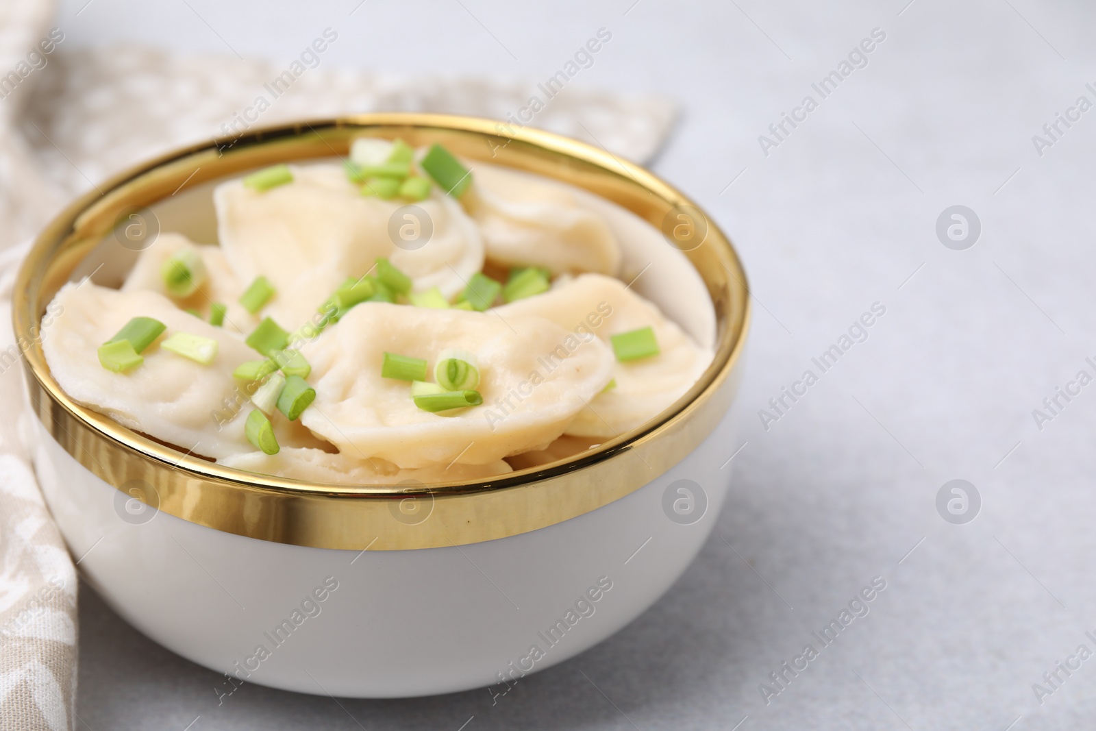 Photo of Cooked dumplings (varenyky) with tasty filling and green onion on light table, closeup