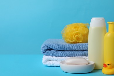 Baby cosmetic products, bath duck, sponge and towels on light blue background. Space for text