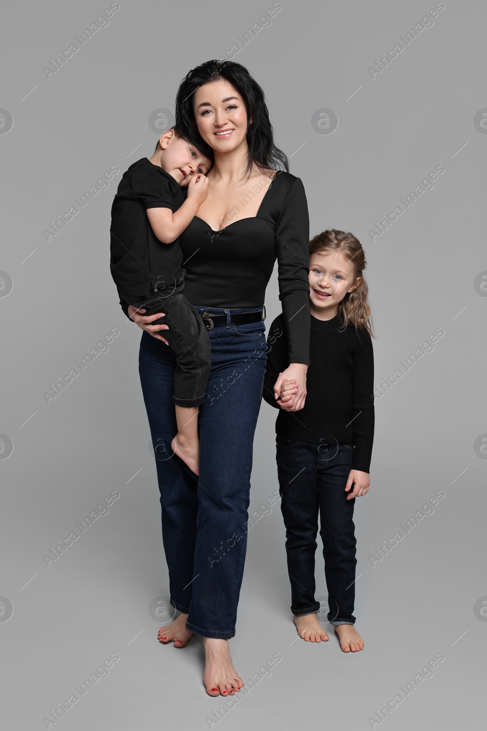 Photo of Little children with their mother on grey background