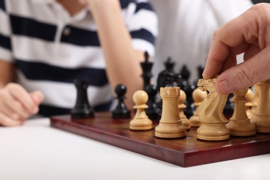 Photo of Senior man playing chess with his grandson, closeup