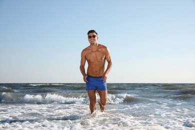 Photo of Handsome man with attractive body running on beach