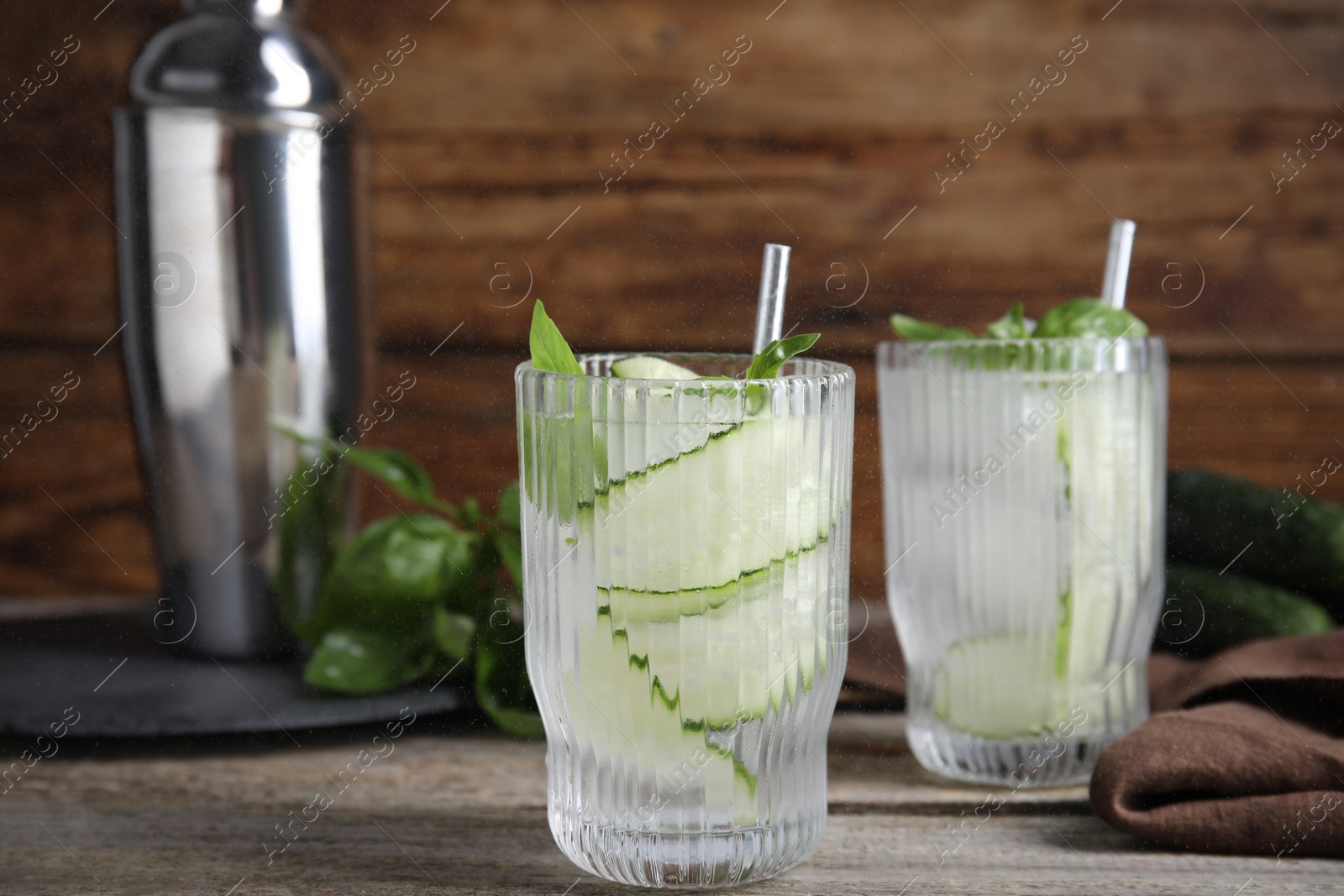 Photo of Glasses of refreshing cucumber water with basil on wooden table