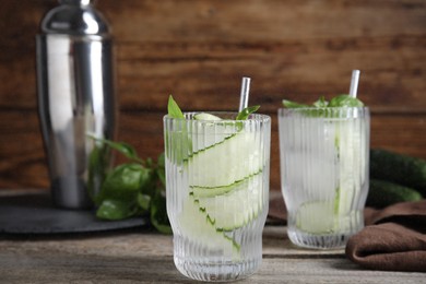 Glasses of refreshing cucumber water with basil on wooden table