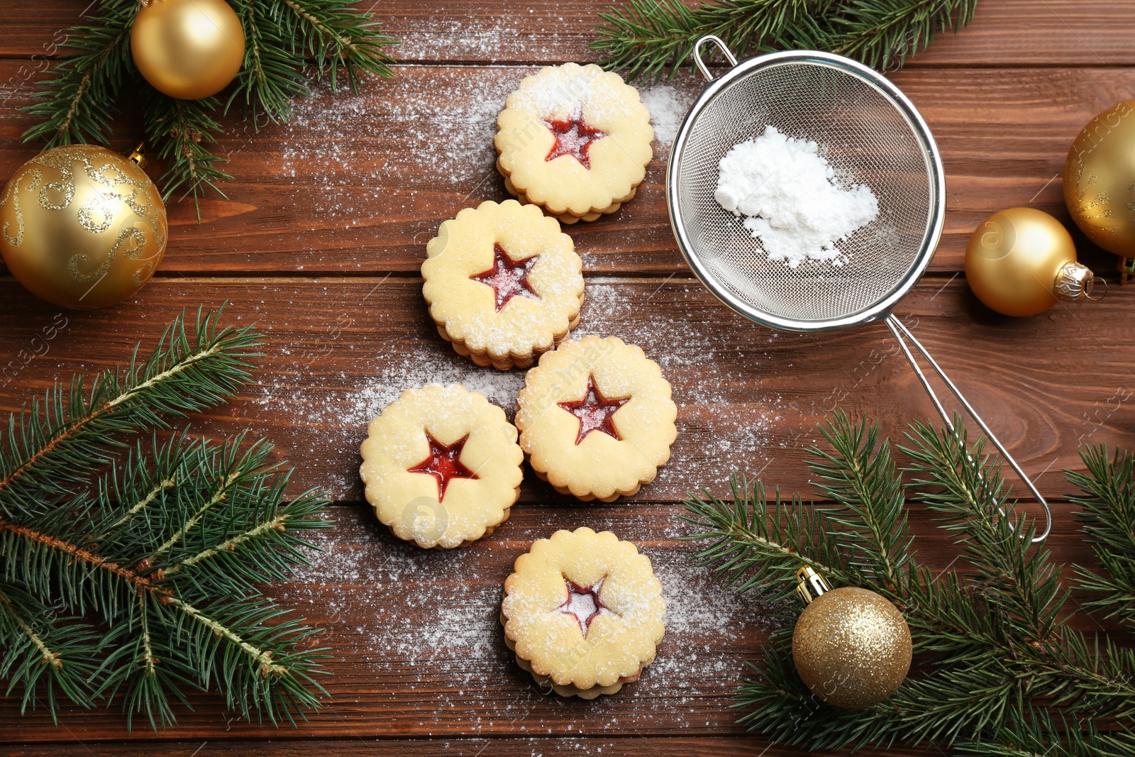 Photo of Linzer cookies with sweet jam and Christmas decorations on wooden background, top view