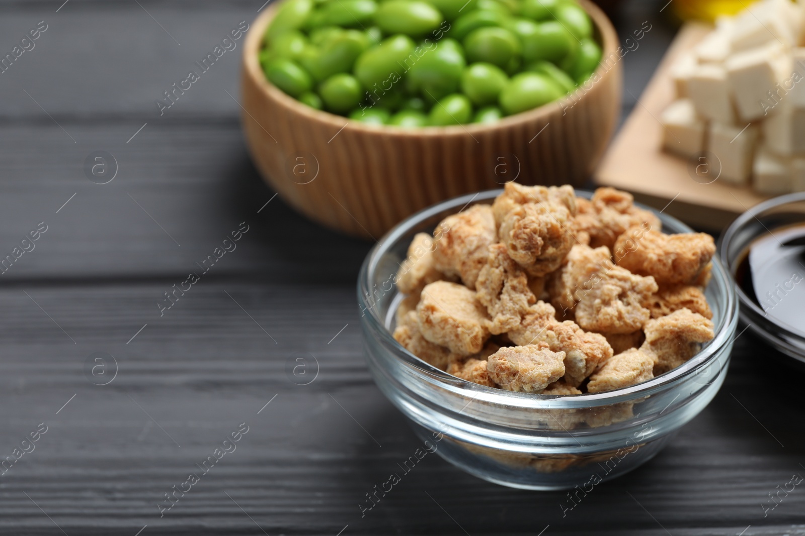 Photo of Dehydrated soy meat and other organic products on grey wooden table, closeup. Space for text