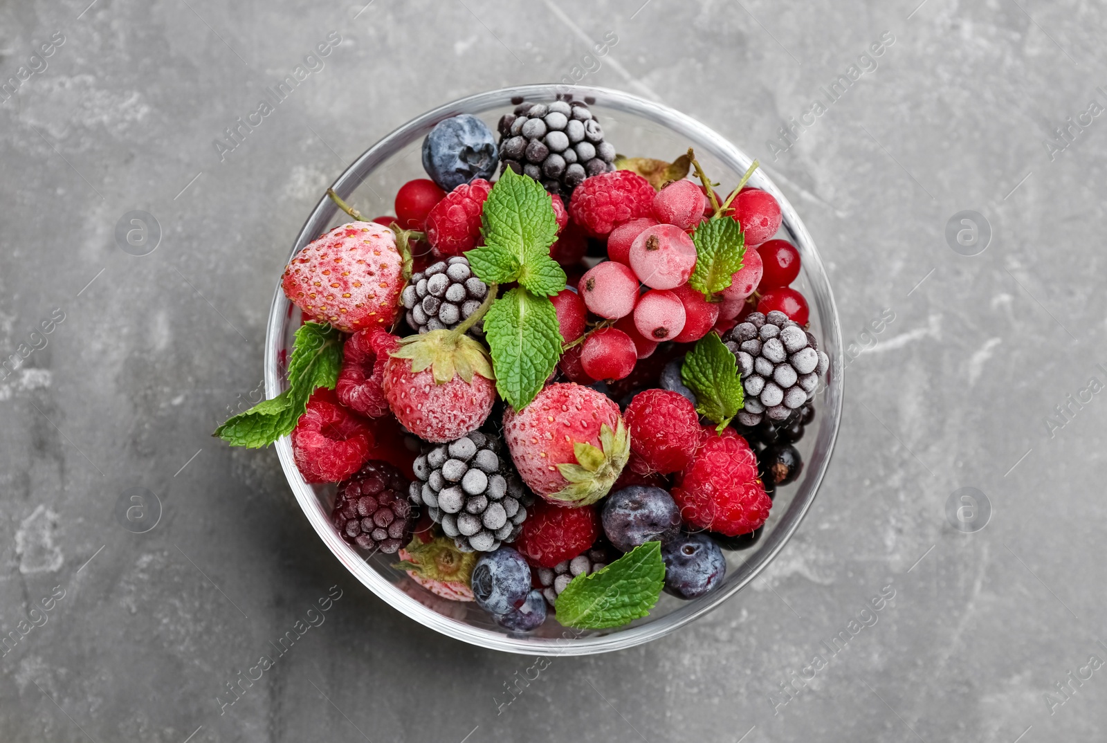 Photo of Mix of different frozen berries in bowl on grey table, top view