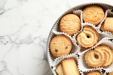 Photo of Tin box with Danish butter cookies on marble table, top view. Space for text