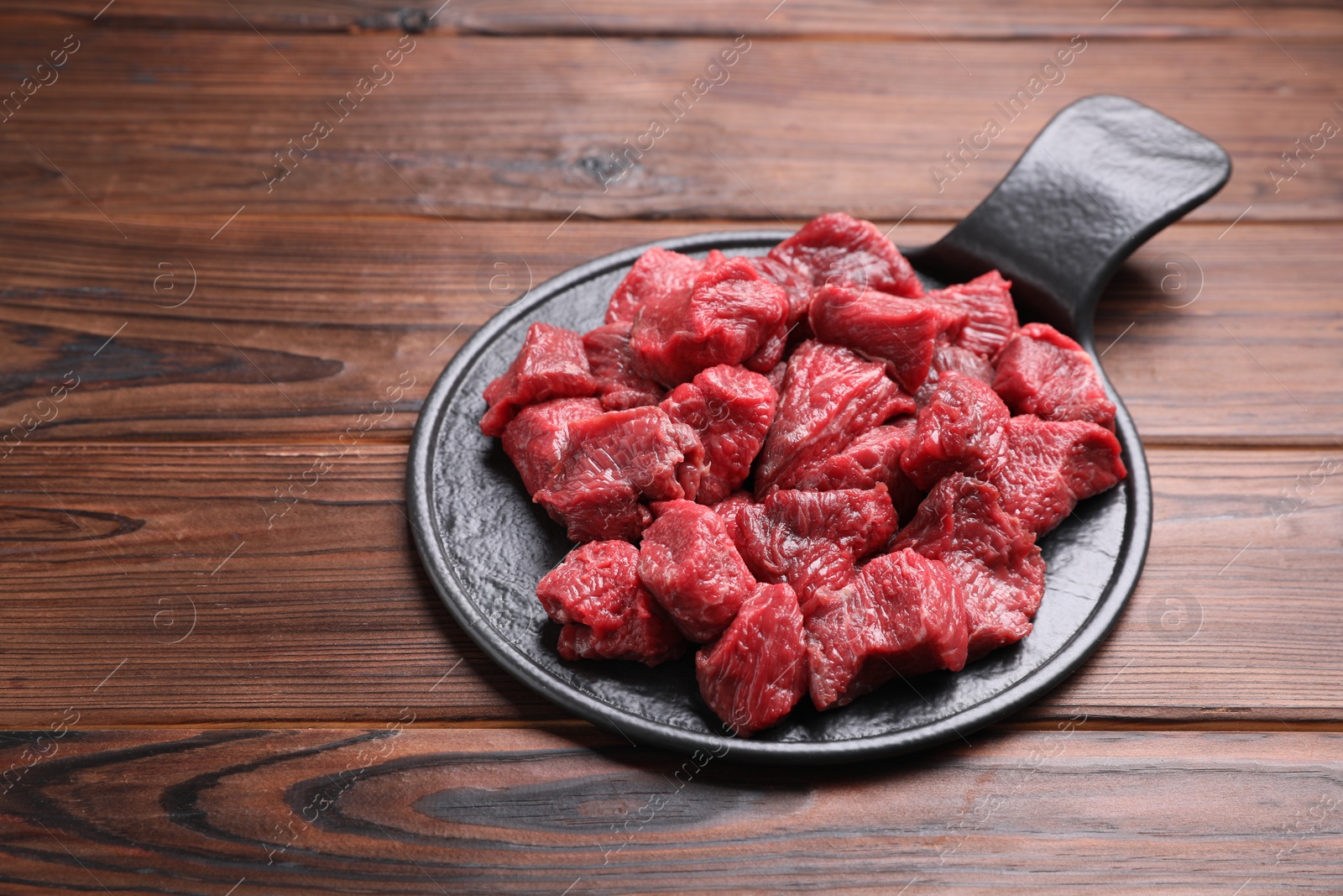 Photo of Pieces of raw beef meat on wooden table. Space for text