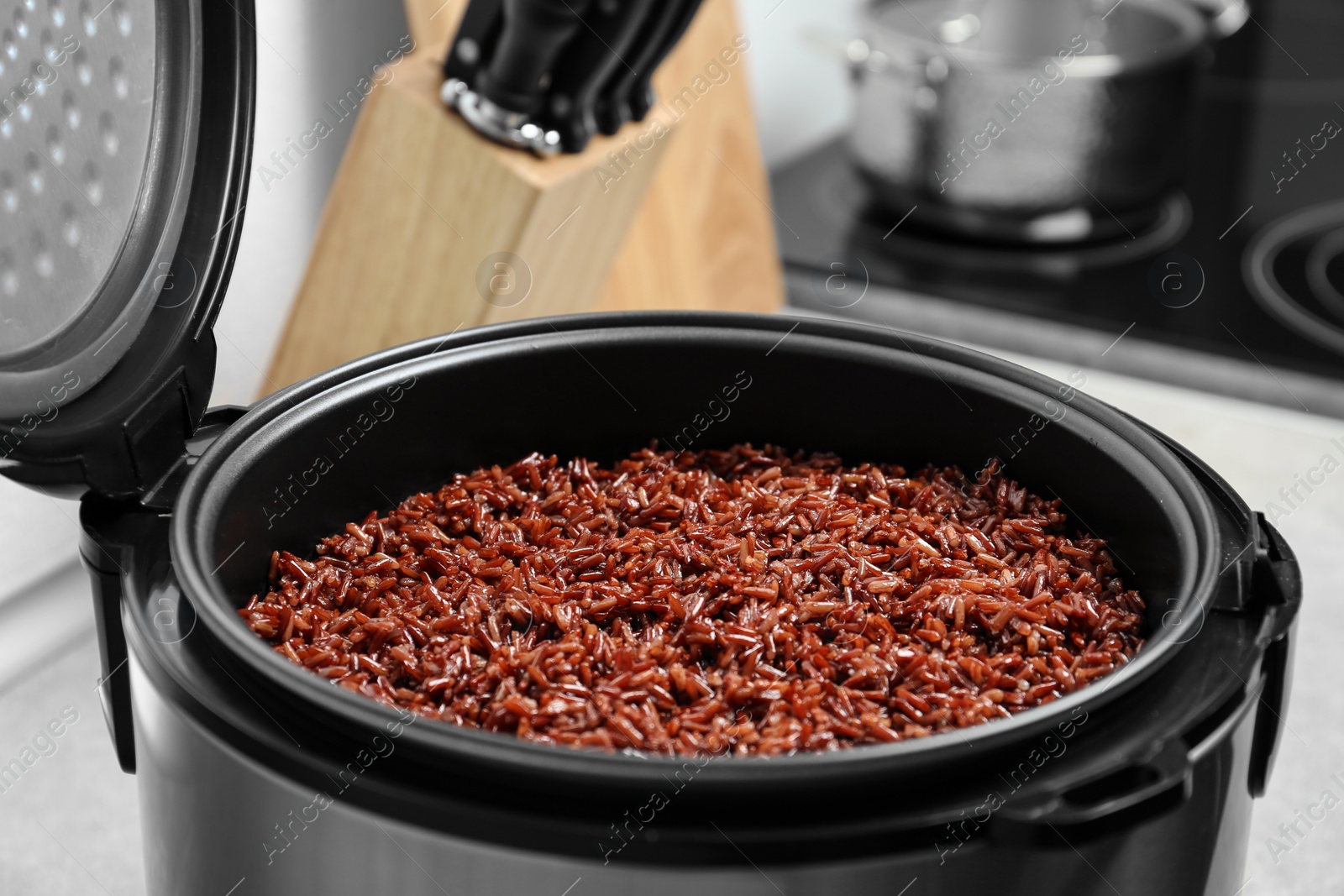 Photo of Modern multi cooker with boiled brown rice in kitchen, closeup