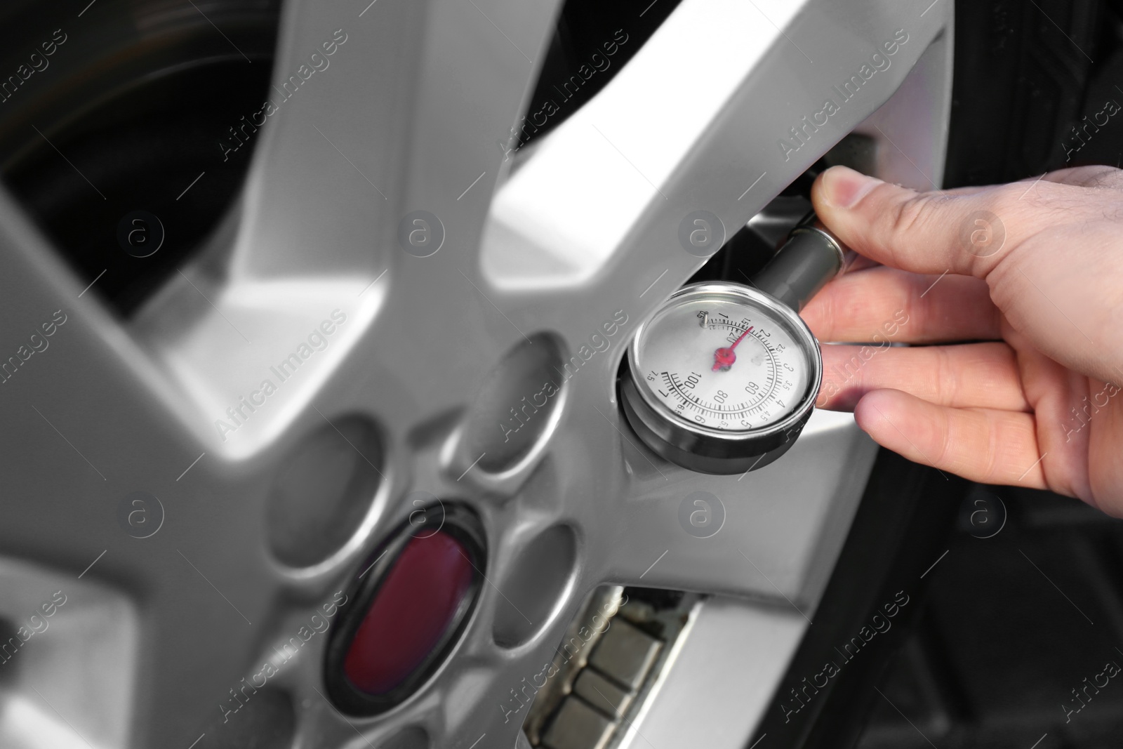 Photo of Mechanic checking tire air pressure at car service, closeup