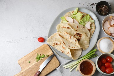 Photo of Cooking pita wrap. Delicious tortillas, chicken, lettuce and other ingredients on light gray table, flat lay. Space for text