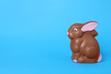 Photo of Chocolate bunny on light blue background, space for text. Easter celebration