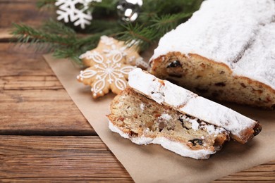 Photo of Traditional Christmas Stollen with icing sugar on wooden table, space for text