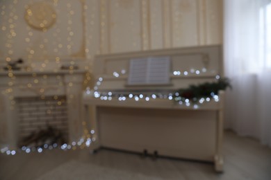 Photo of Blurred view of white piano with festive decor indoors. Christmas music