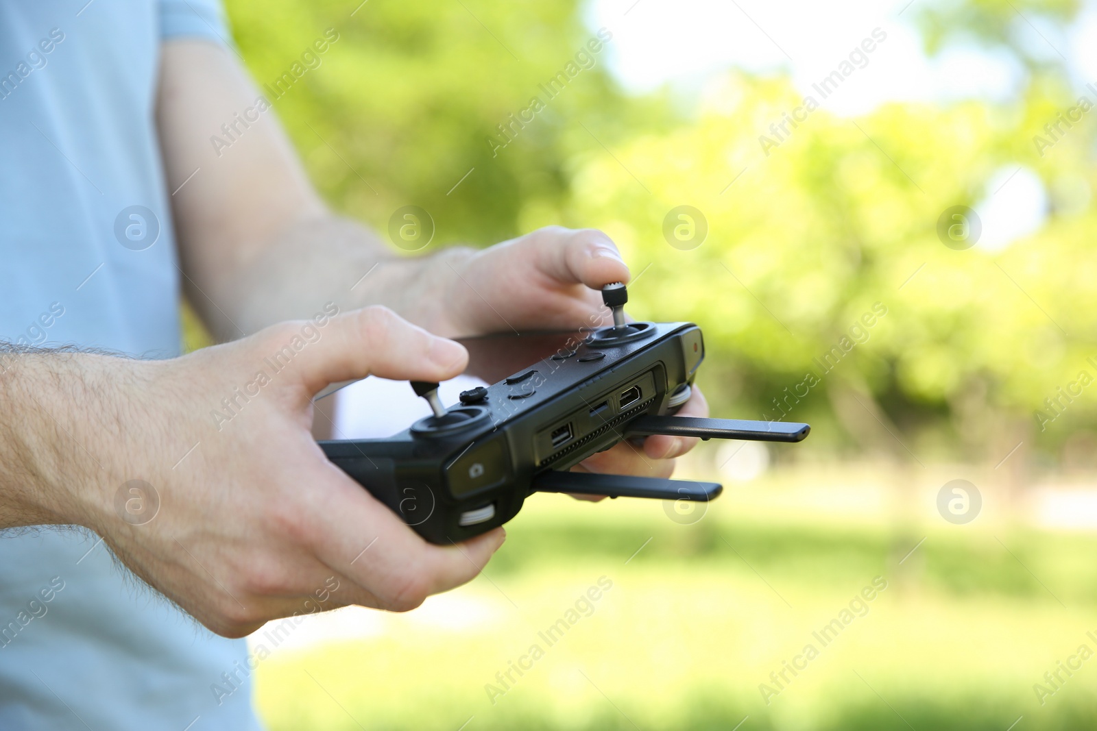 Photo of Man holding new modern drone controller outdoors, closeup of hands