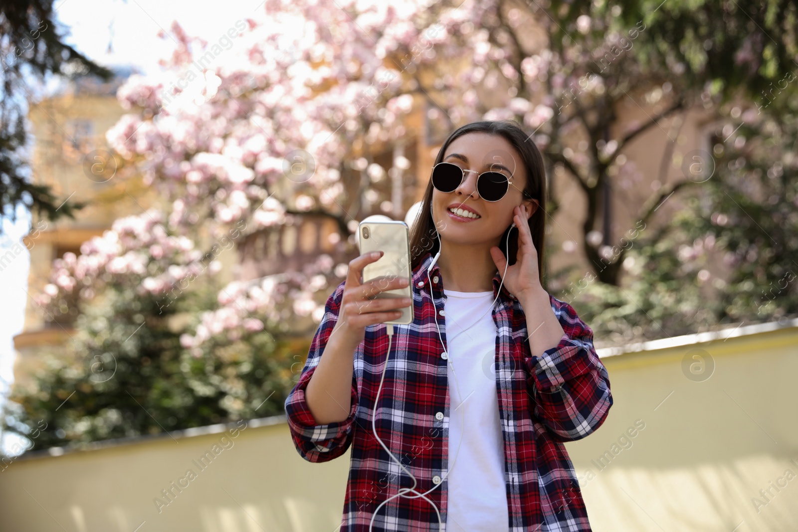 Photo of Young woman listening to audiobook in park