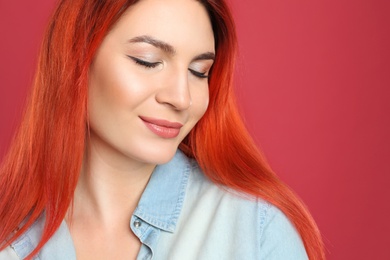 Photo of Young woman with bright dyed long hair on red background, closeup