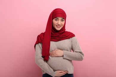 Photo of Portrait of pregnant Muslim woman in hijab on pink background