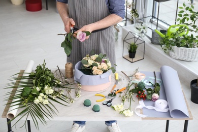 Photo of Male florist pruning rose at workplace