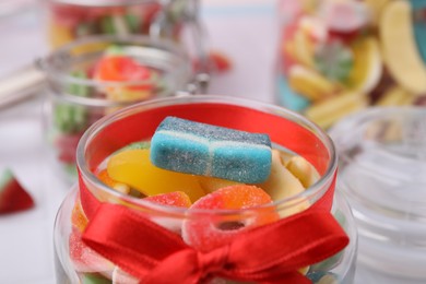 Glass jar with tasty colorful jelly candies on table, closeup