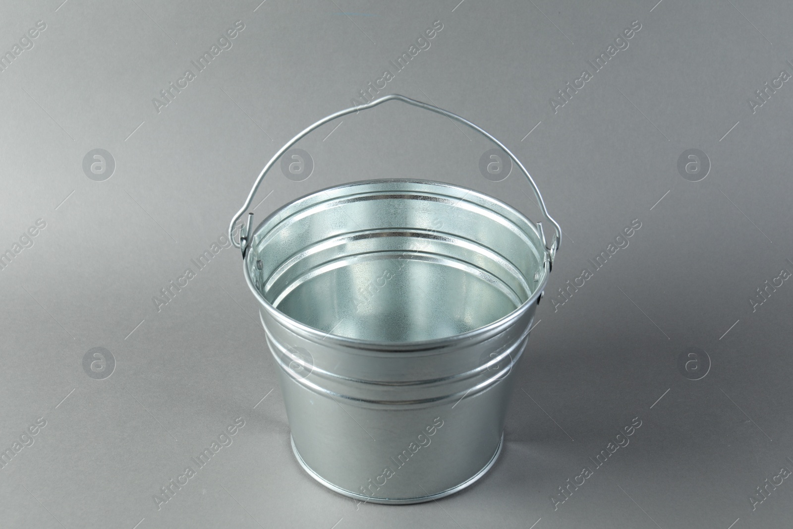 Photo of One shiny metal bucket on light grey background