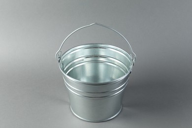 Photo of One shiny metal bucket on light grey background