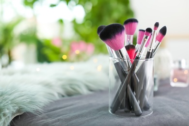 Makeup brushes in holder on blurred background