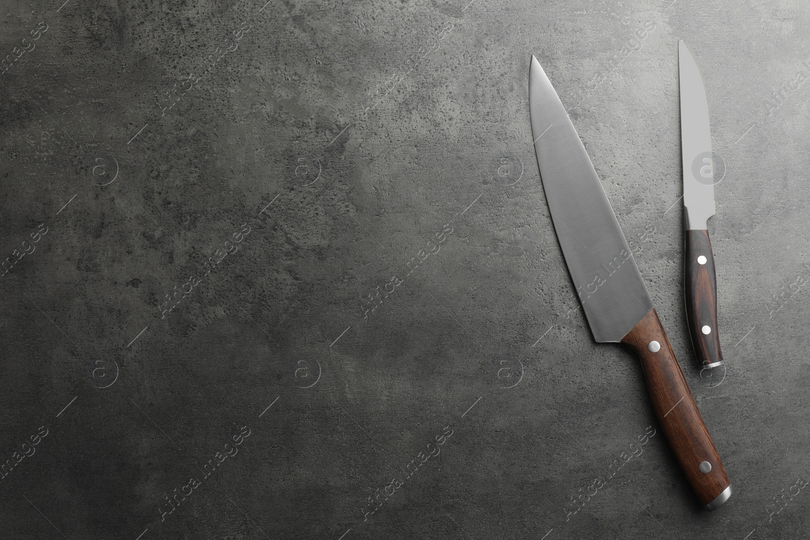 Photo of Knives on grey textured table, flat lay. Space for text