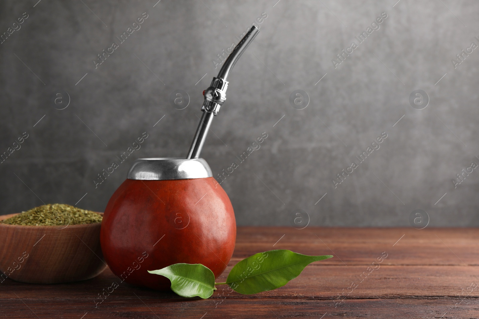 Photo of Calabash with mate tea and bombilla on wooden table. Space for text