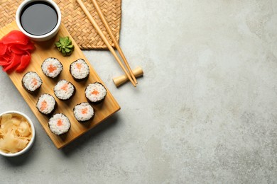 Photo of Tasty sushi rolls served on grey table, flat lay. Space for text