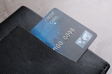 Credit card in leather wallet on grey textured table, closeup