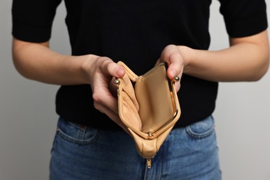 Woman with empty wallet on light grey background, closeup