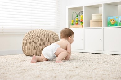 Photo of Baby boy crawling on carpet at home, back view