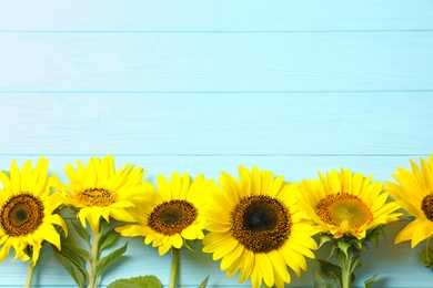 Photo of Yellow sunflowers on wooden background, top view