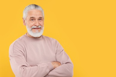 Portrait of handsome senior man on orange background. Space for text