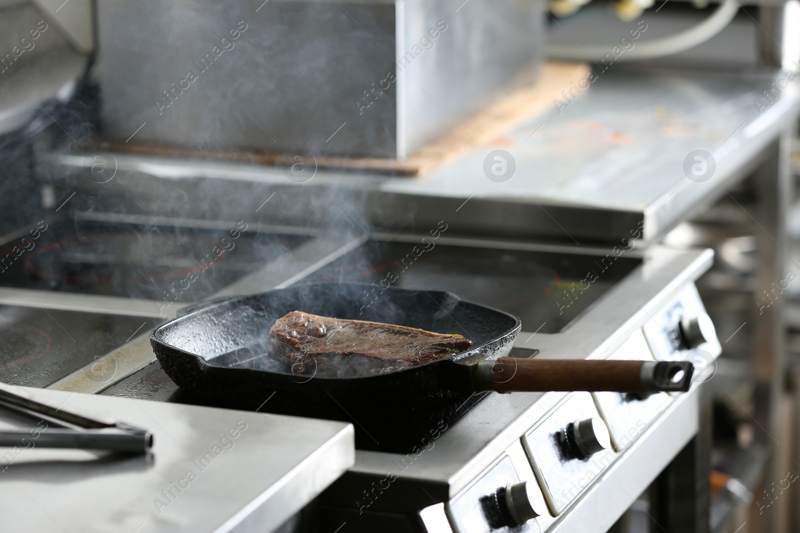 Photo of Cooking delicious meat on frying pan in restaurant kitchen