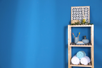 Photo of Shelving unit with toiletries near blue wall indoors, space for text. Bathroom interior element