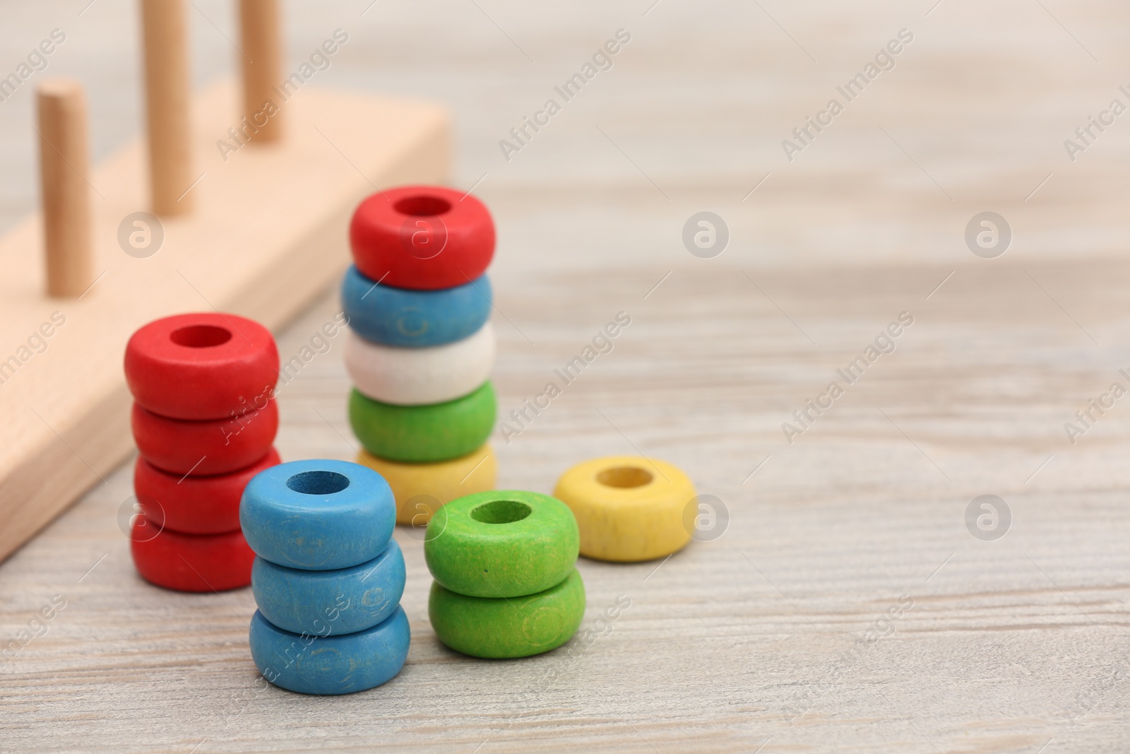 Photo of Motor skills development. Stacking and counting game pieces on light wooden table, space for text