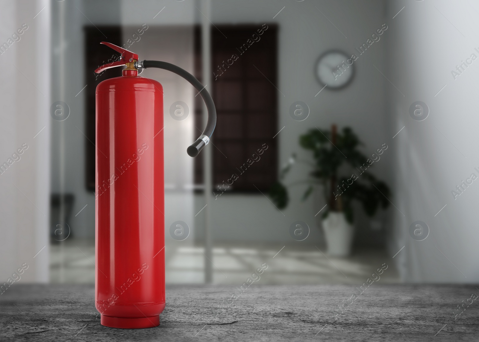 Image of Fire extinguisher on black slate table indoors. Space for text